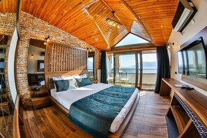 A bedroom with a large bed, wooden ceiling, and a view of the sea. - Diamond Liman Hotel (Amasra)