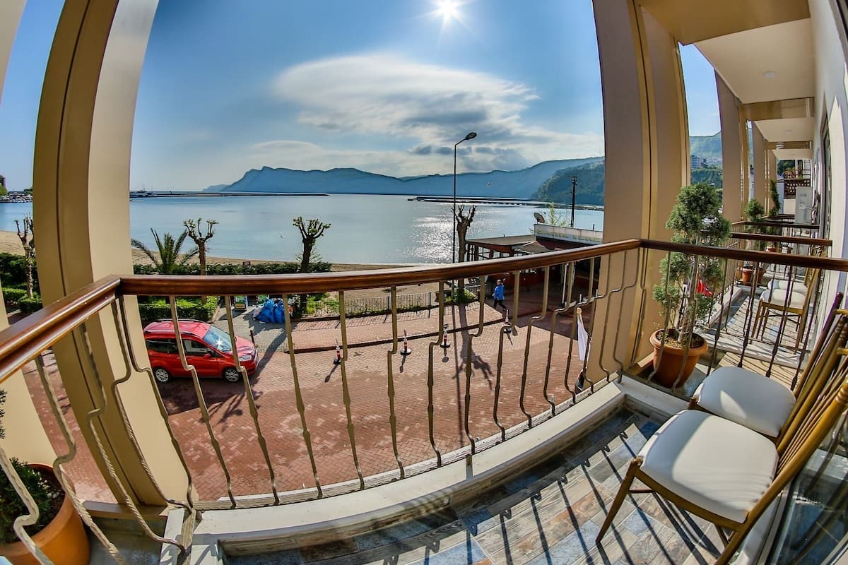 A balcony with a view of a body of water, mountains, and a clear sky.