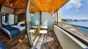 A balcony with a wooden ceiling and glass walls, overlooking a body of water and a distant town. - Diamond Liman Hotel (Amasra)