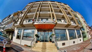 A multi-story hotel with a central atrium, balconies on each floor, and a prominent entrance with a wooden canopy. - Diamond Liman Hotel (Amasra)