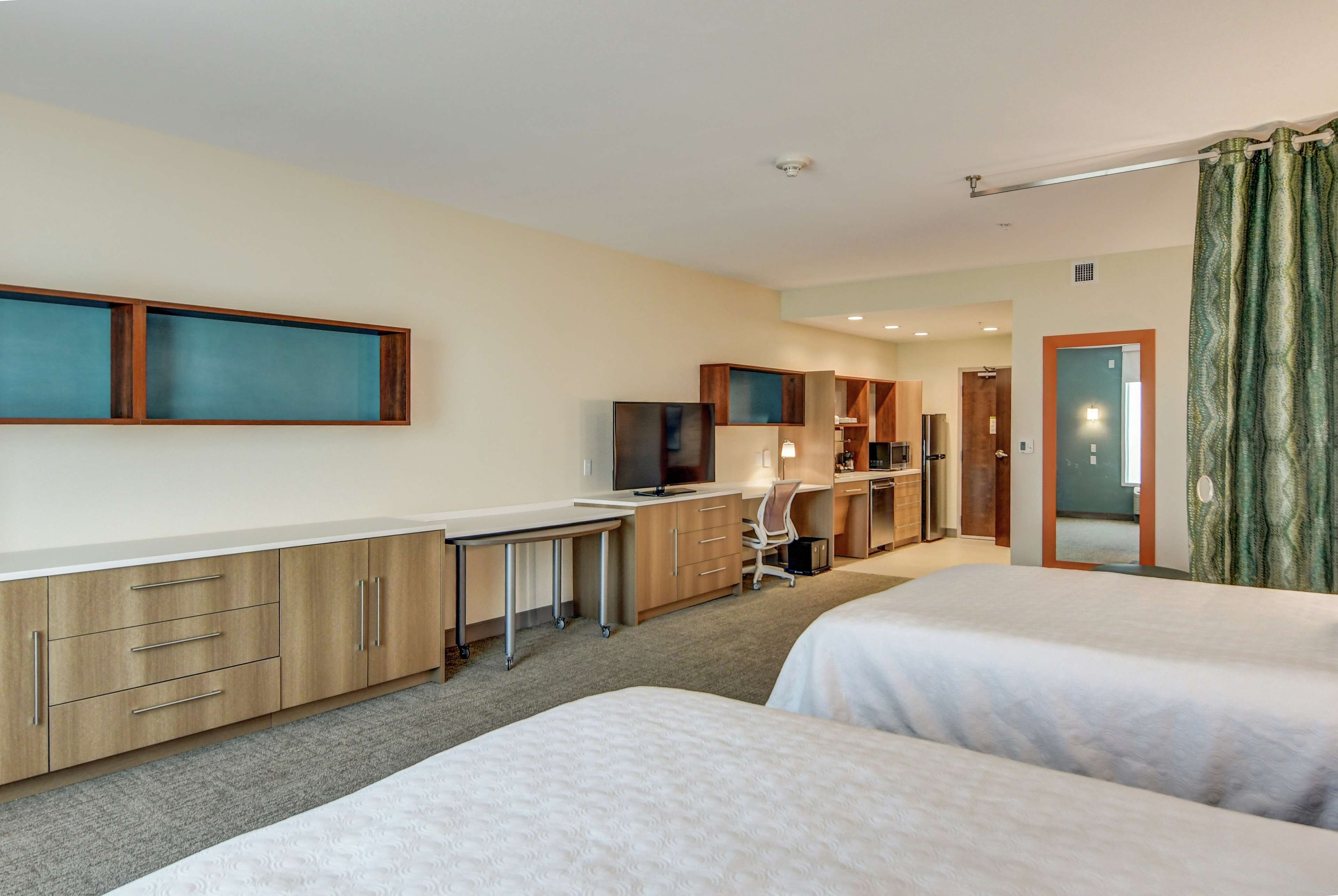 Ett hotellrum med två sängar, ett skrivbord, en tv och ett badrum som syns genom en öppen dörr.