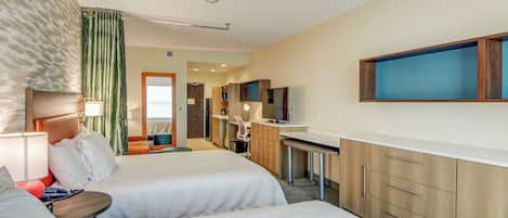 Ett hotellrum med två sängar, ett skrivbord, en tv och ett badrum som syns i bakgrunden.