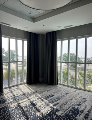 A room with large windows, a patterned carpet, and a ceiling with recessed lighting. - Hilton Garden Inn Biloxi (Biloxi)