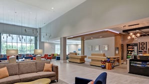 A spacious lobby with a sofa, armchairs, and a reception desk. - Hilton Garden Inn Biloxi (Biloxi)
