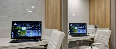 Un espacio de oficina moderno con dos escritorios, cada uno con una computadora portátil y teclado, y una silla de cuero blanco.