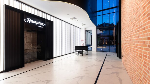 A modern interior with a Hampton store, a bench, and a brick wall. - Hampton by Hilton Kalisz (Kalisz)