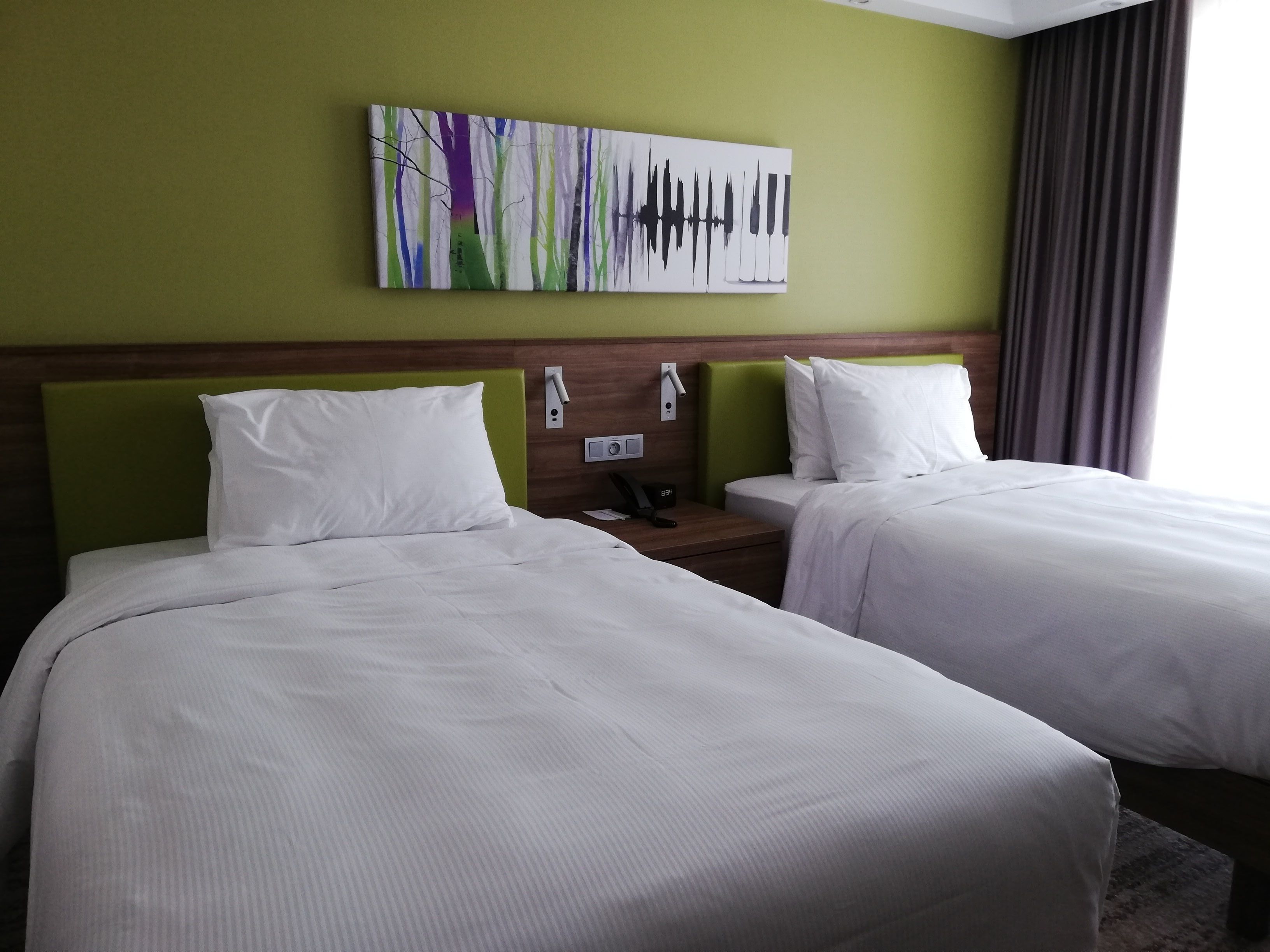 Habitación de hotel con dos camas, una mesita de noche con teléfono y un cuadro en la pared.