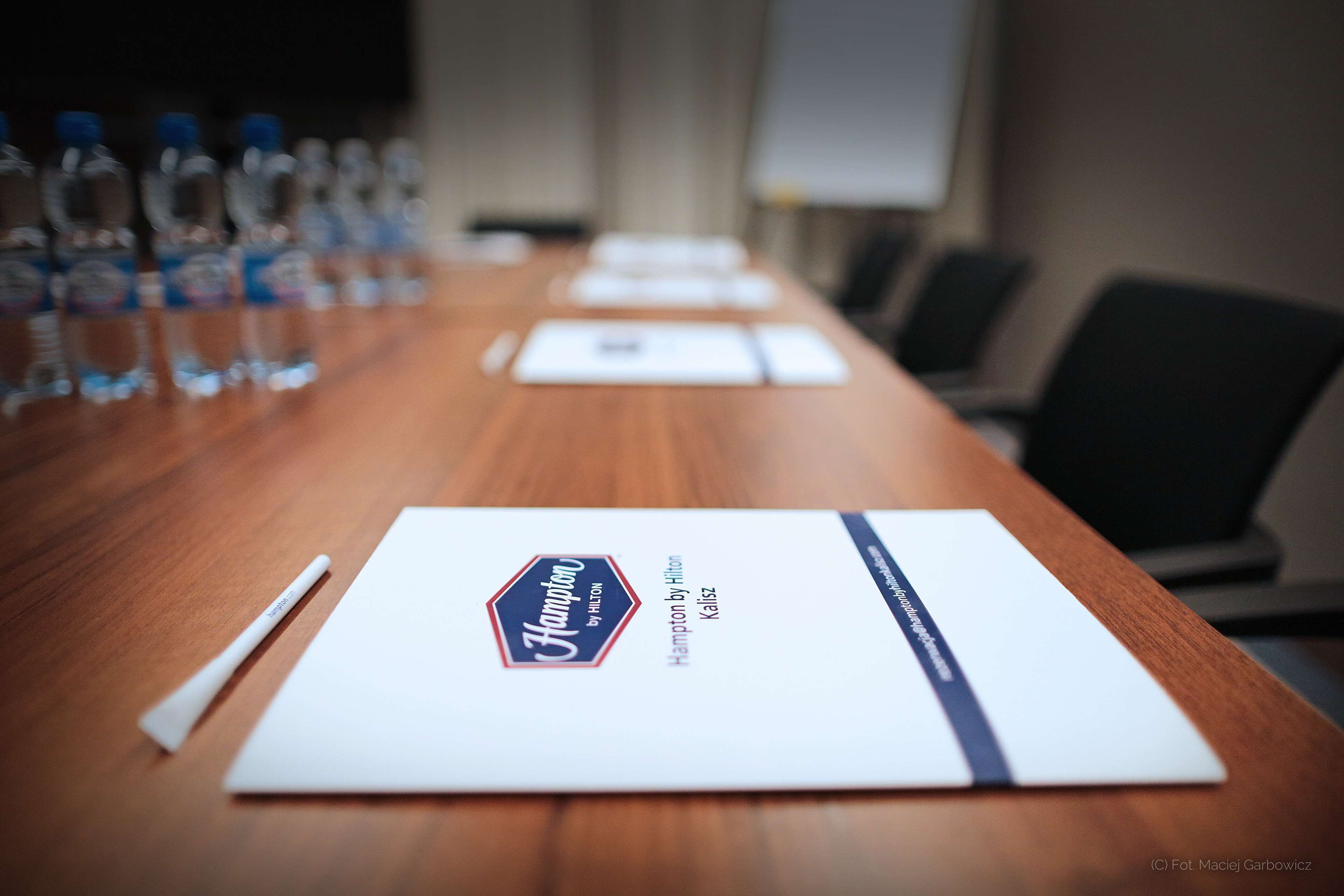 A conference table with name cards, water bottles, and a whiteboard in a meeting room.