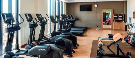 A gym with multiple treadmills, a rowing machine, and a mirror.