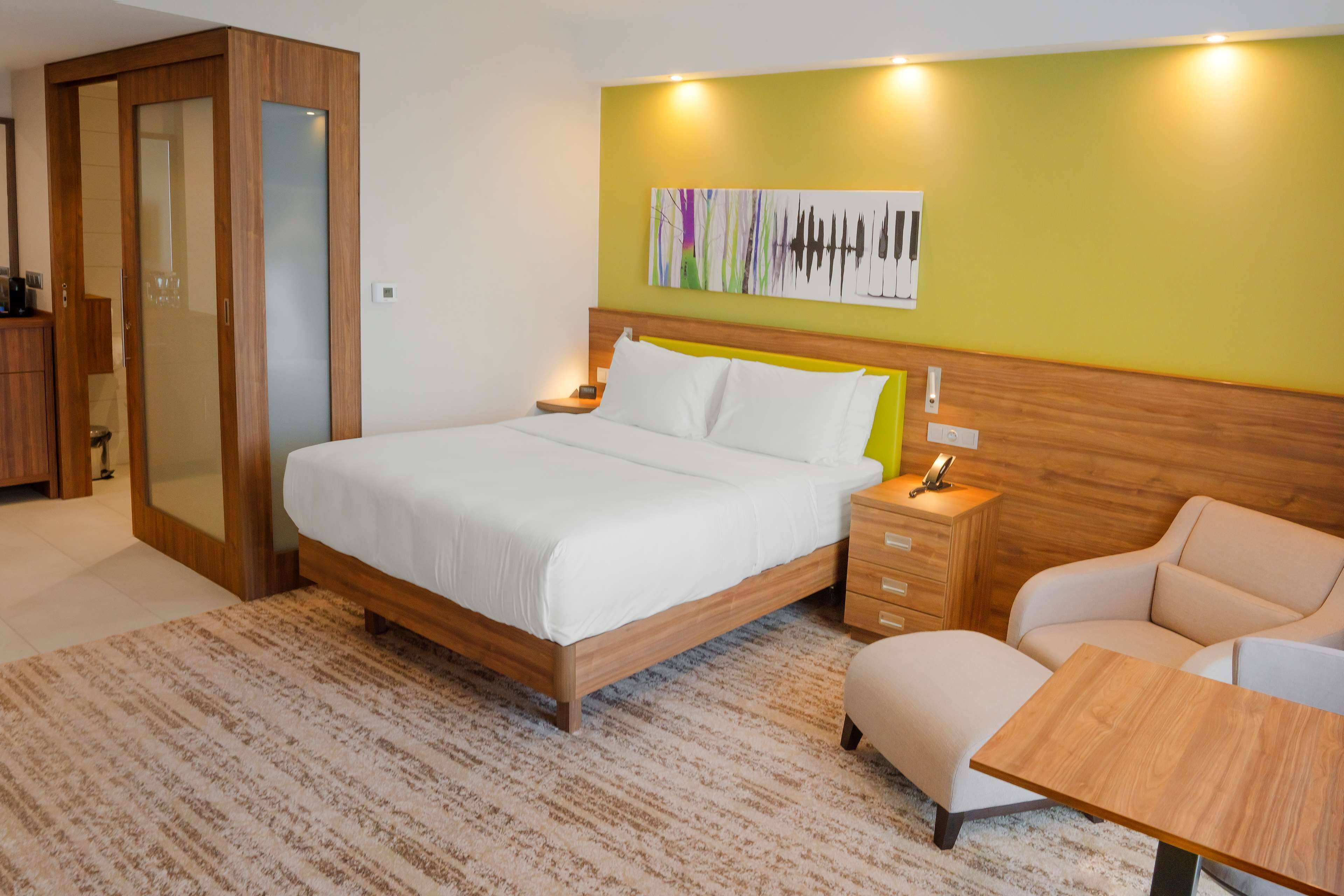 Un dormitorio moderno con cama, mesitas de noche, una silla y cabecera de madera.