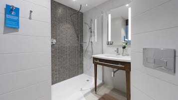 Une salle de bain moderne avec une douche, un lavabo et un miroir.
