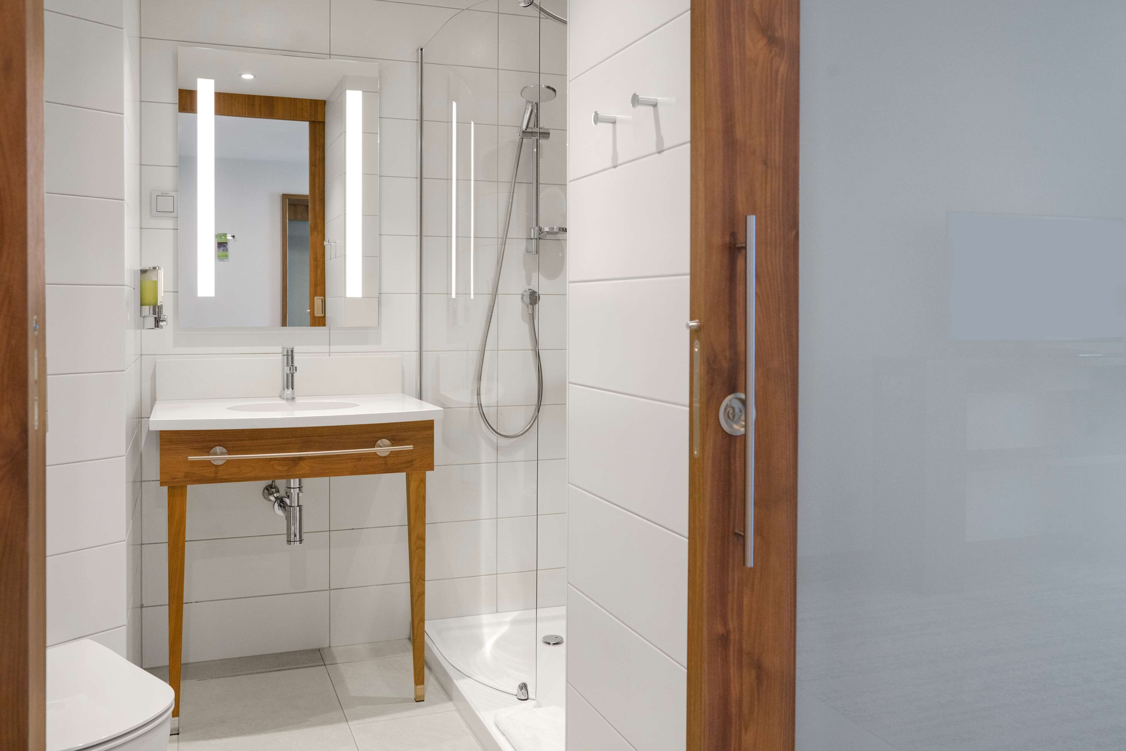 Une salle de bain moderne avec un lavabo blanc, un meuble-lavabo en bois et une cabine de douche en verre.