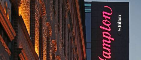 Letrero de hotel con el nombre "Hampton by Hilton" en un edificio moderno.