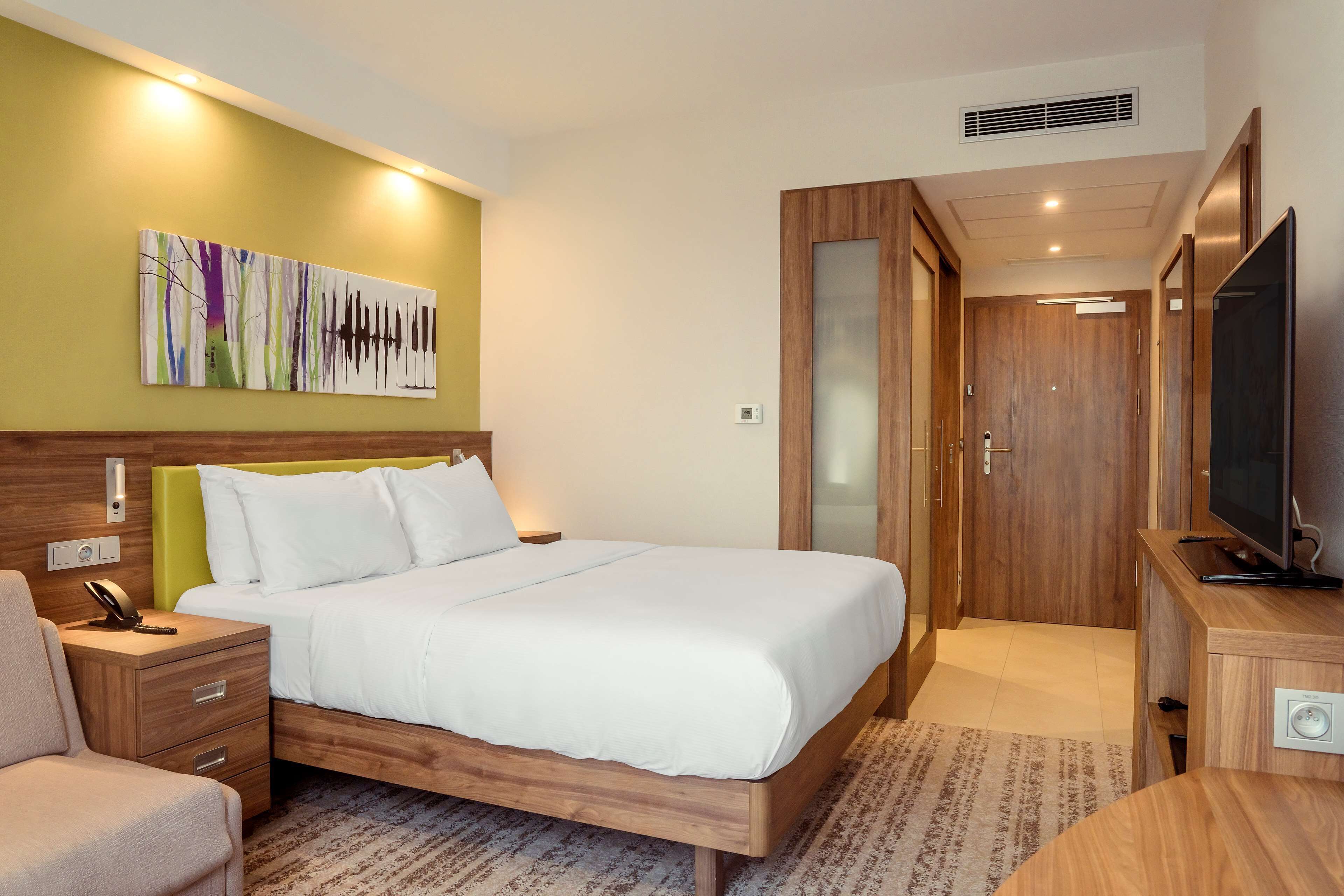 Une chambre d’hôtel avec un lit, des tables de chevet, une télévision et un tableau au mur.