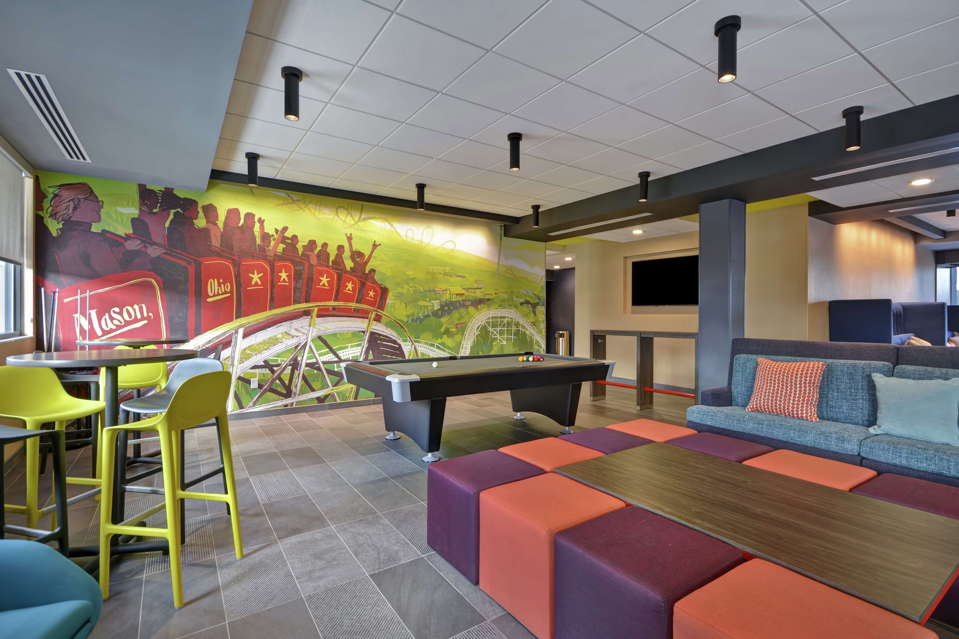 A pool table, seating area, and a mural with a Ferris wheel.