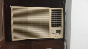 Un climatiseur fixé sur une porte en bois foncé, avec un panneau de verre en dessous.