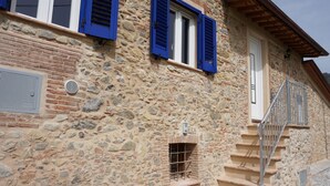 A stone building with blue shutters, a small window, and a staircase.