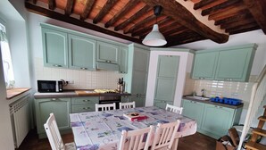 A kitchen with teal cabinets, a wooden ceiling, and a dining table set with chairs.