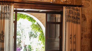 A doorway with a chandelier, patterned curtains, and a view of an outdoor garden. - Likya Yolu Palas (Demre)