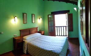 Une chambre à coucher comprenant un lit, des tables de chevet, une armoire et une porte donnant sur un espace extérieur.