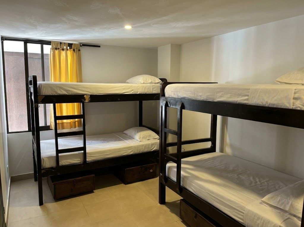 A bunk bed room with a window, curtains, and a ceiling light.