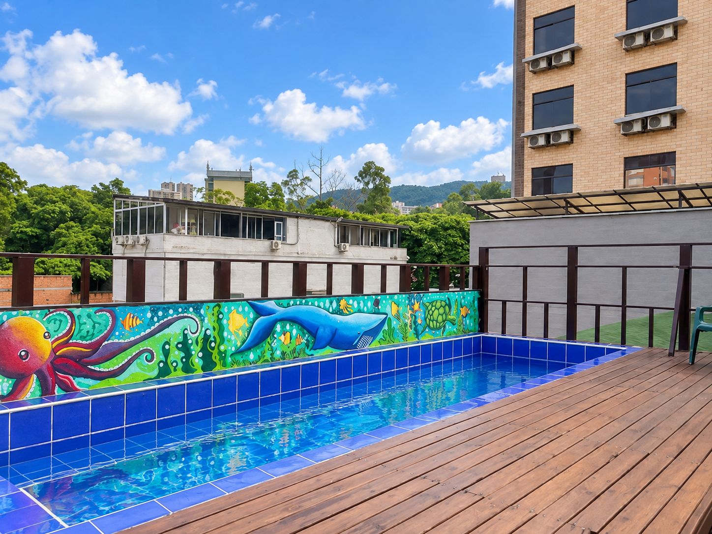 A swimming pool with a colorful mural on the wall, surrounded by a wooden deck.