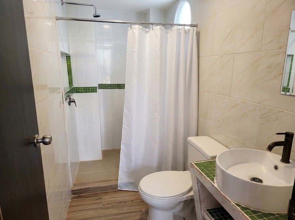 Een badkamer met douche, toilet en wastafel.