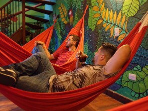 Una habitación con una hamaca, un mural con hojas tropicales y una escalera.
