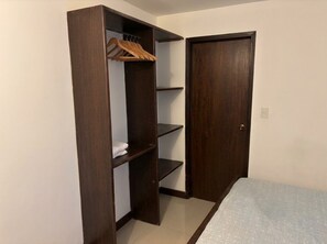 Una habitación con armario, cama y puerta.