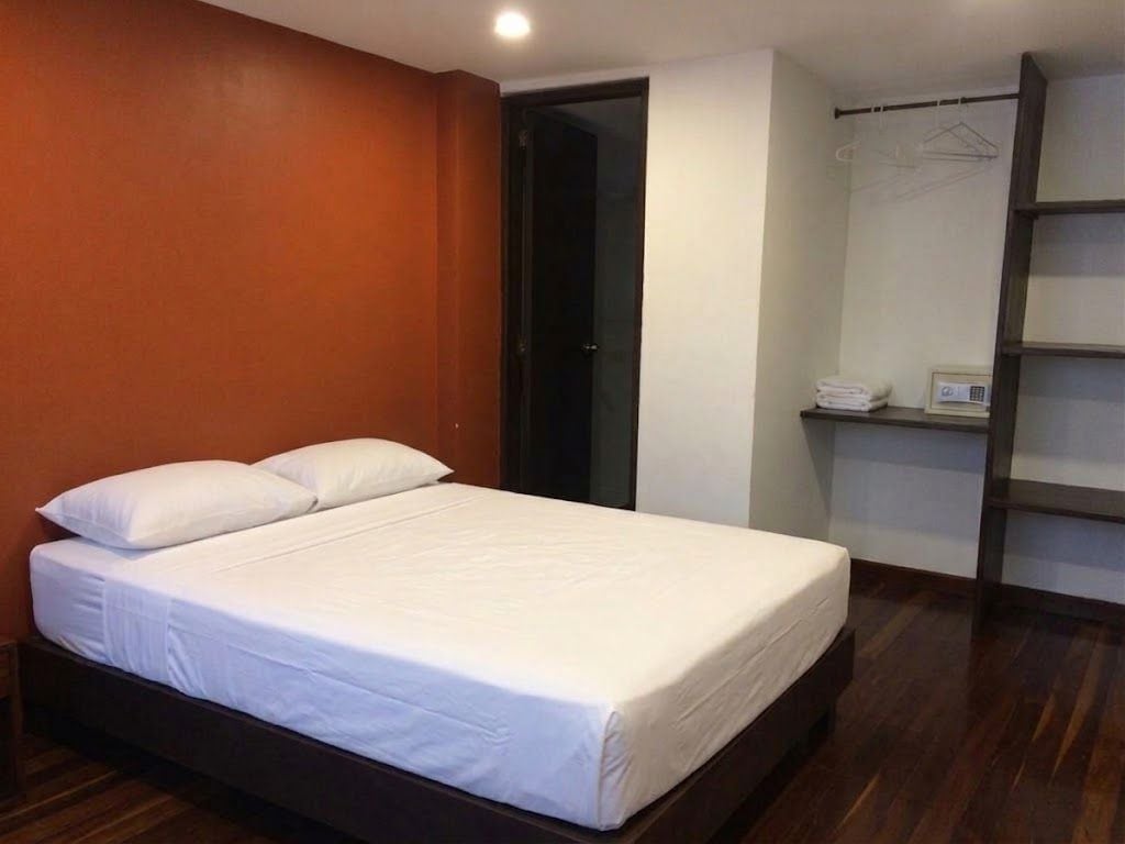 A bedroom with a bed, a wardrobe, and a shelf with items.