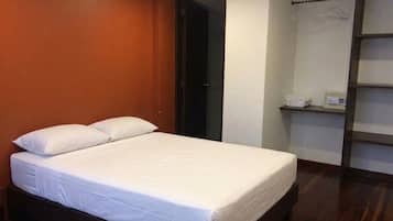 A bedroom with a bed, a wardrobe, and a shelf with items.
