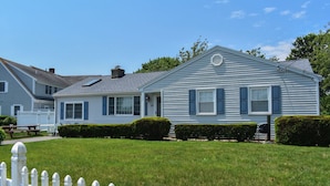 A two-story house with a front porch, a small attached garage, and a well-maintained lawn.