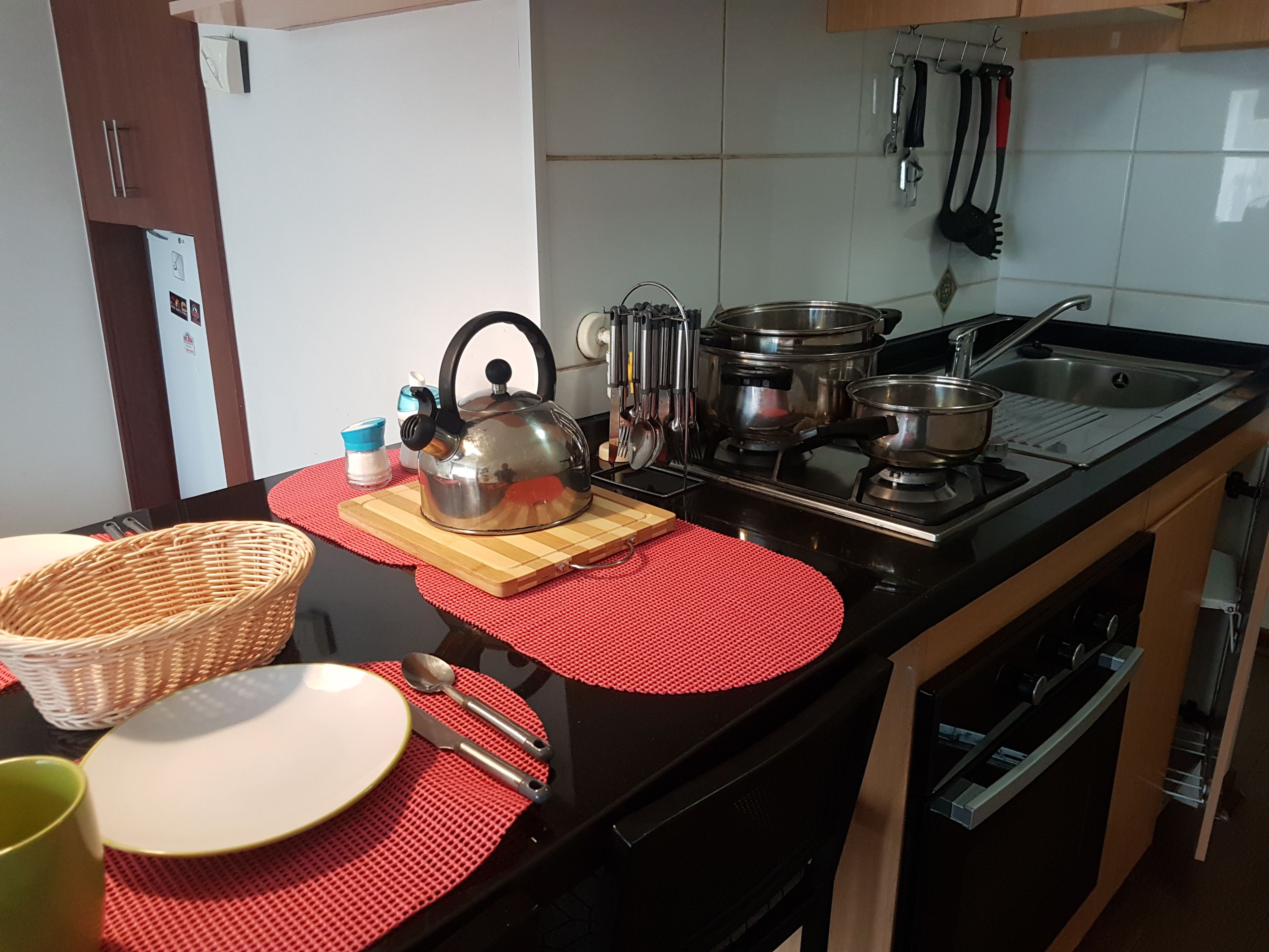 Une cuisine équipée d’une cuisinière, de casseroles, d’une bouilloire et de divers ustensiles.