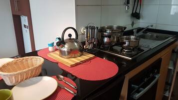 Une cuisine équipée d’une cuisinière, de casseroles, d’une bouilloire et de divers ustensiles.