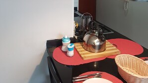 A kitchen with wooden shelves, a hanging pendant light, and a dining area with a red placemat. - Apart Reñaca C-206 (Vina del Mar)
