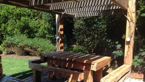 An outdoor wooden picnic table with a built-in sink, set against a backdrop of lush greenery and a wooden pergola. - Apart Reñaca C-206 (Vina del Mar)