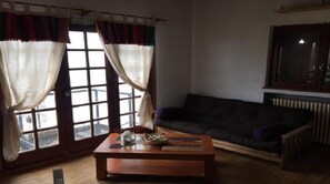 Ein Wohnzimmer mit einem dunkelgrauen Sofa, einem Holztisch und einem Fenster mit Vorhängen.
