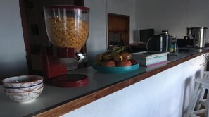 Eine Küchenarbeitsplatte mit einem Mixer, einer Obstschale und einer Kaffeemaschine.