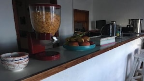 Una encimera de cocina con una licuadora, un tazón de fruta y una cafetera.