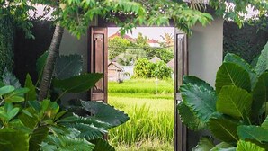 Un sendero en un jardín que lleva a una puerta enmarcada por abundante vegetación.