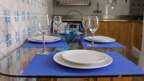 A dining table set with plates and wine glasses, blue placemats, and a decorative blue vase.