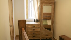 A wooden dresser with drawers and a mirror, positioned next to a window with curtains.