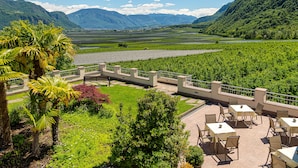 A terrace with outdoor seating overlooking a lush valley and mountains. - Hotel Wilma (Nalles)