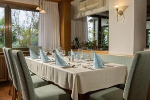A dining area with a table set for four, chairs, and a view of the outdoors. - Hotel Wilma (Nalles)