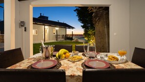 An outdoor dining area with a table set for two, featuring plates, cutlery, and a variety of food items. - Fontana Luxury Private Villa with Pool Nr Beach & Sea Views In Mountain Village (Salakos)