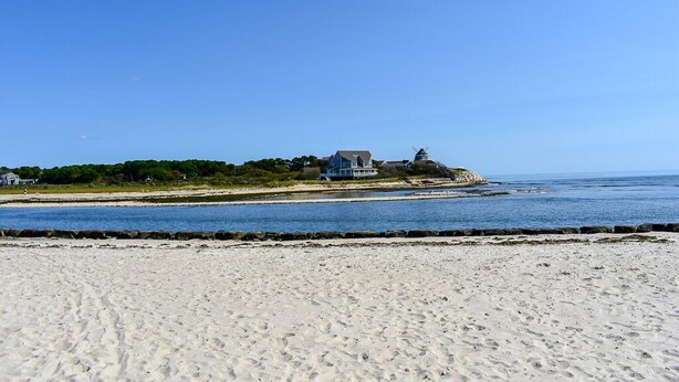 A beach with a house on a cliff overlooking the ocean.