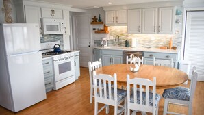 A kitchen with white cabinets, a stove, microwave, and a dining table with chairs.