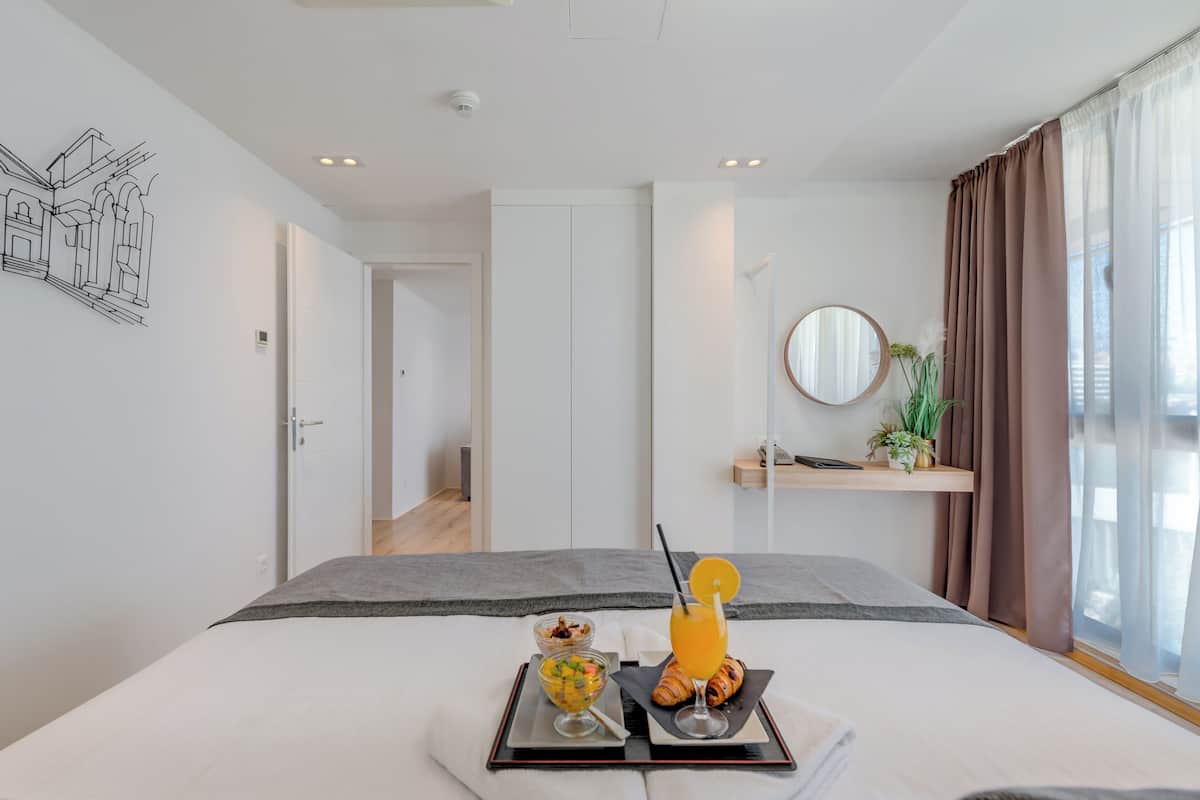 A modern hotel room with a bed, breakfast tray, and a view of the city.