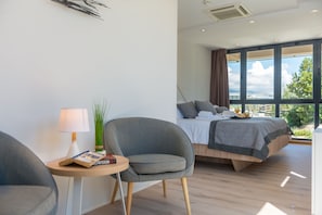 A modern bedroom with a bed, a chair, a small table with a lamp, and a view of the outdoors. - PAX (Split)