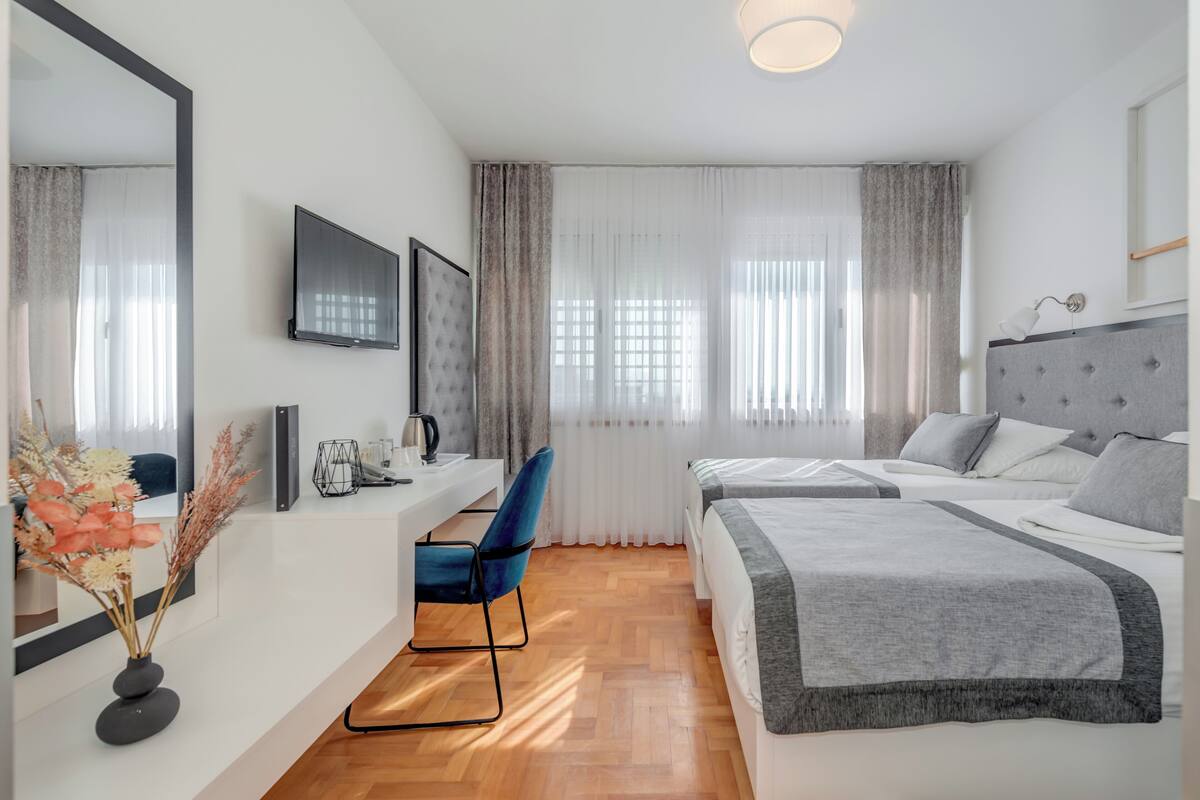 A modern hotel room with a bed, a desk, a chair, and a TV.